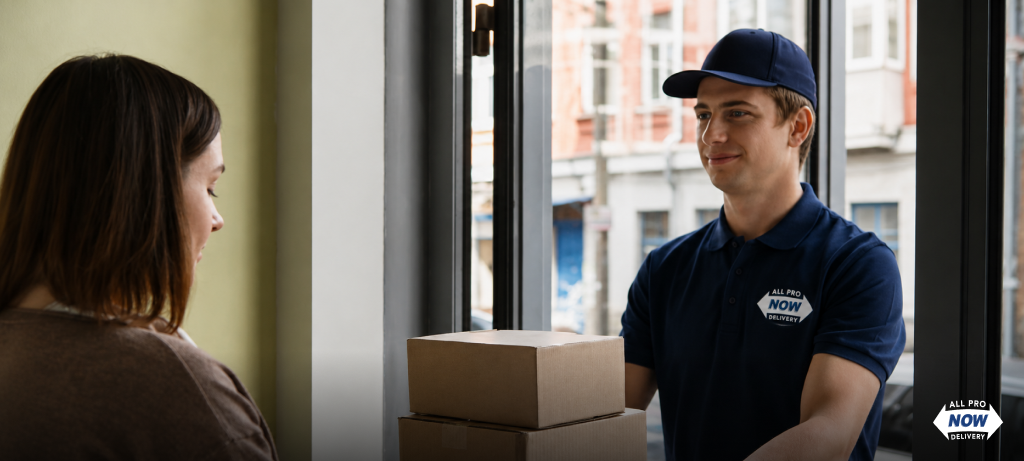 AllProNow delivery driver in branded uniform handing two packages to a homeowner at the front door, representing the last-mile delivery stage